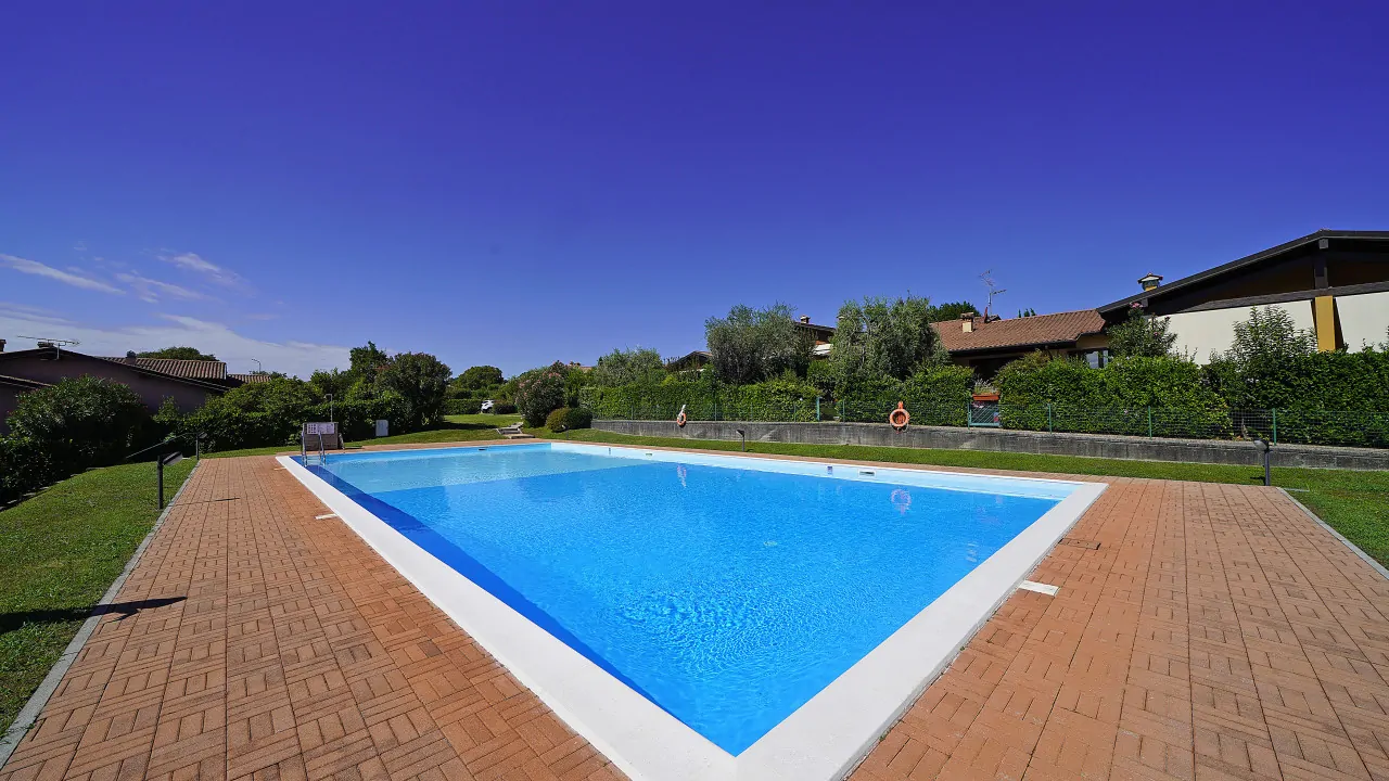 Piscina rettangolare con bordo in mattoni e prato verde