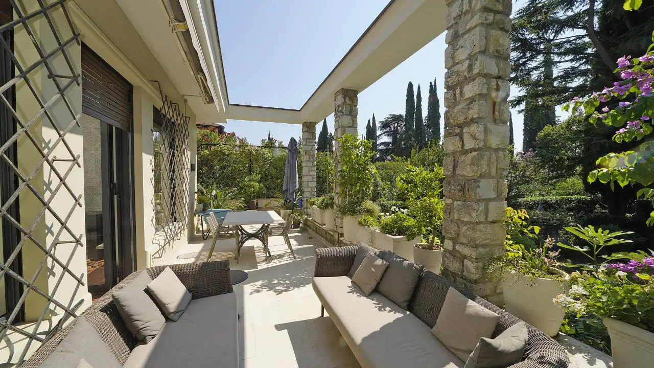 Terrasse mit Sofas und Gartentisch mit Topfpflanzen