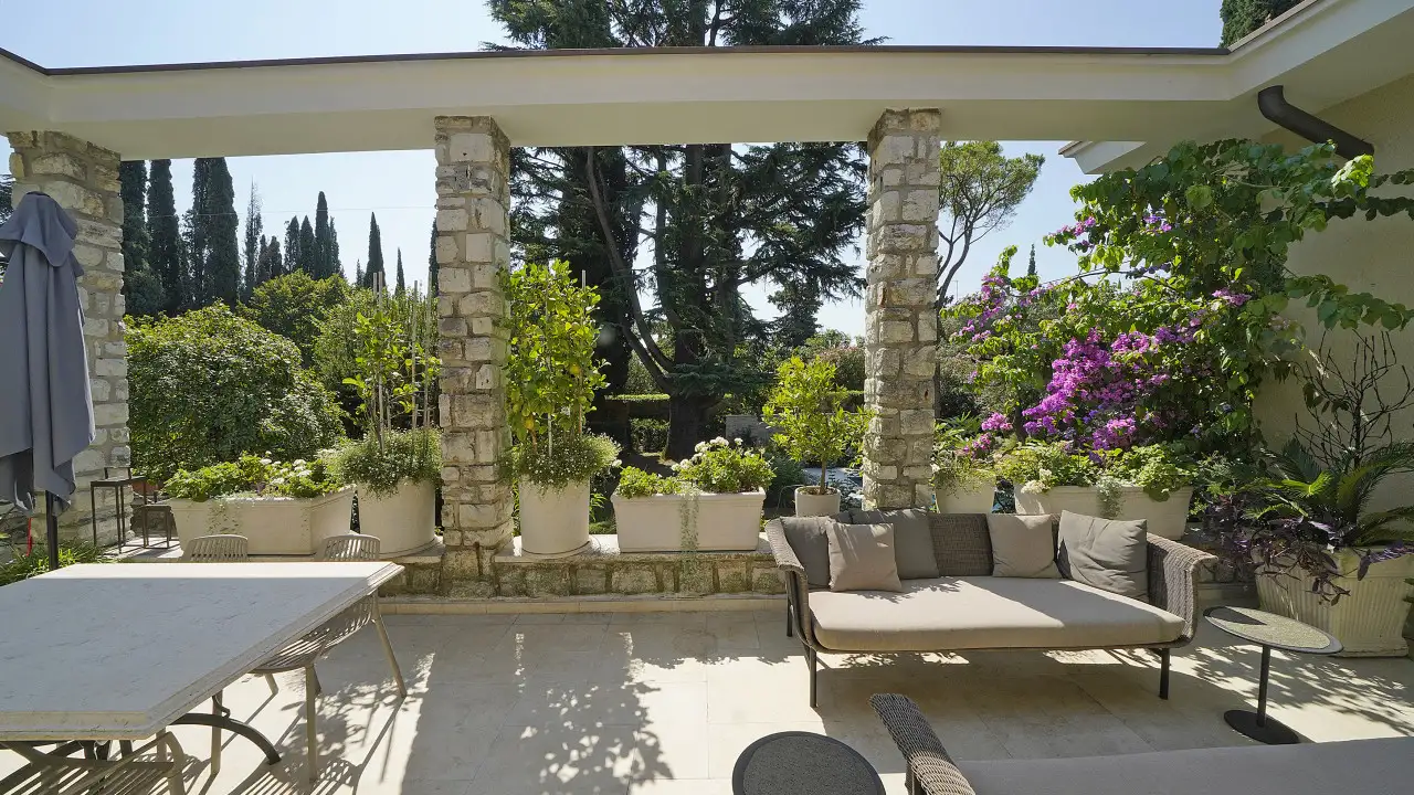 Terrasse mit Sofa und Außentisch mit Topfpflanzen