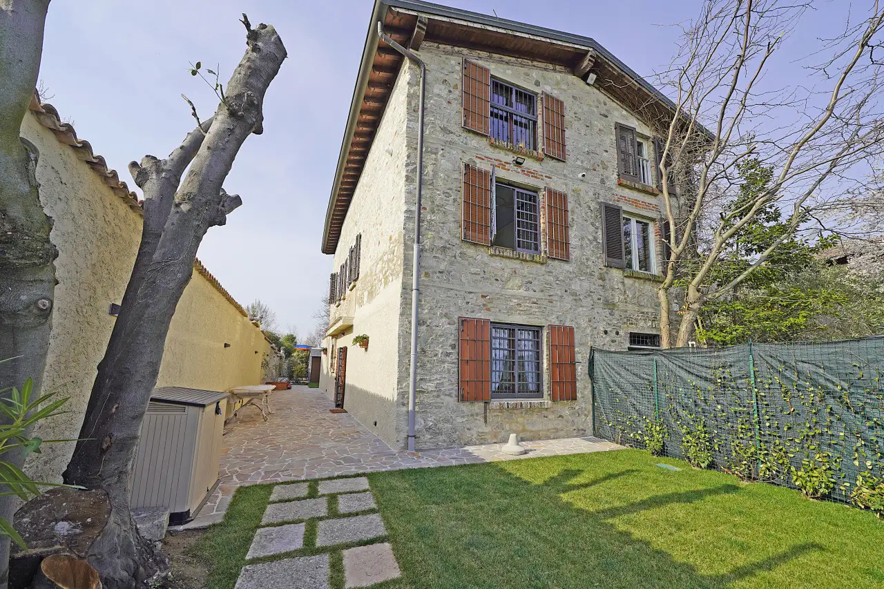 Facciata in pietra con finestre e giardino laterale