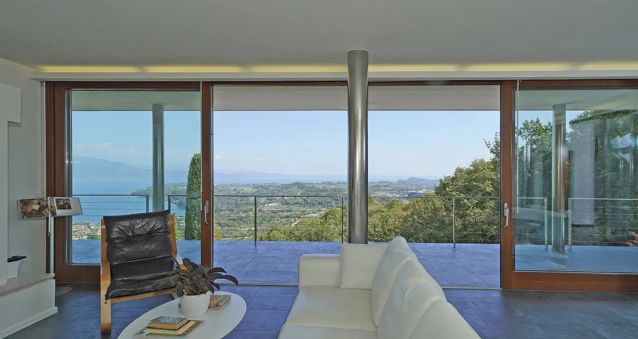 Wohnzimmer mit weißem Sofa und Panoramaverglasung zur Terrasse und Landschaft