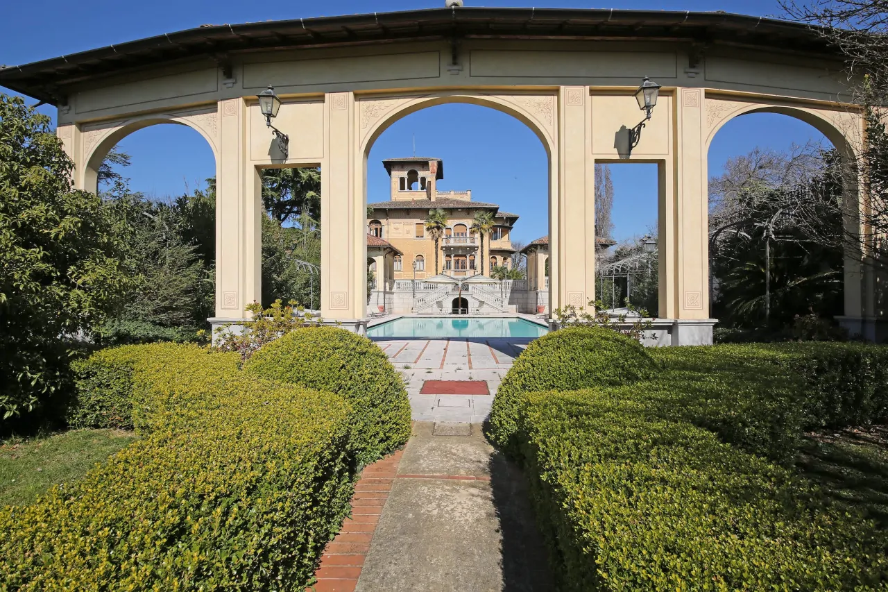 Blick auf die Liberty-Villa durch einen Bogen im Garten mit Pool
