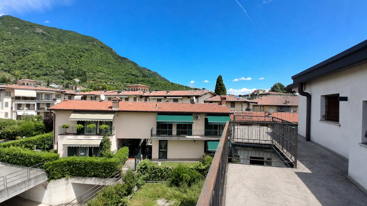 Terrasse mit Metallgeländer und Blick auf Häuser und grünen Hügel