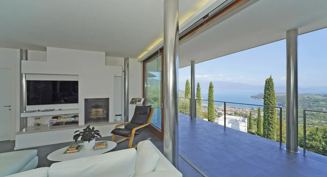 Wohnzimmer mit Kamin und offenem Fenster zur Panoramaterrasse