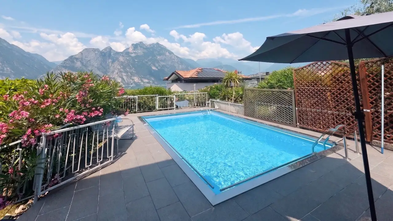 Piscina rettangolare con ombrellone e fioriere