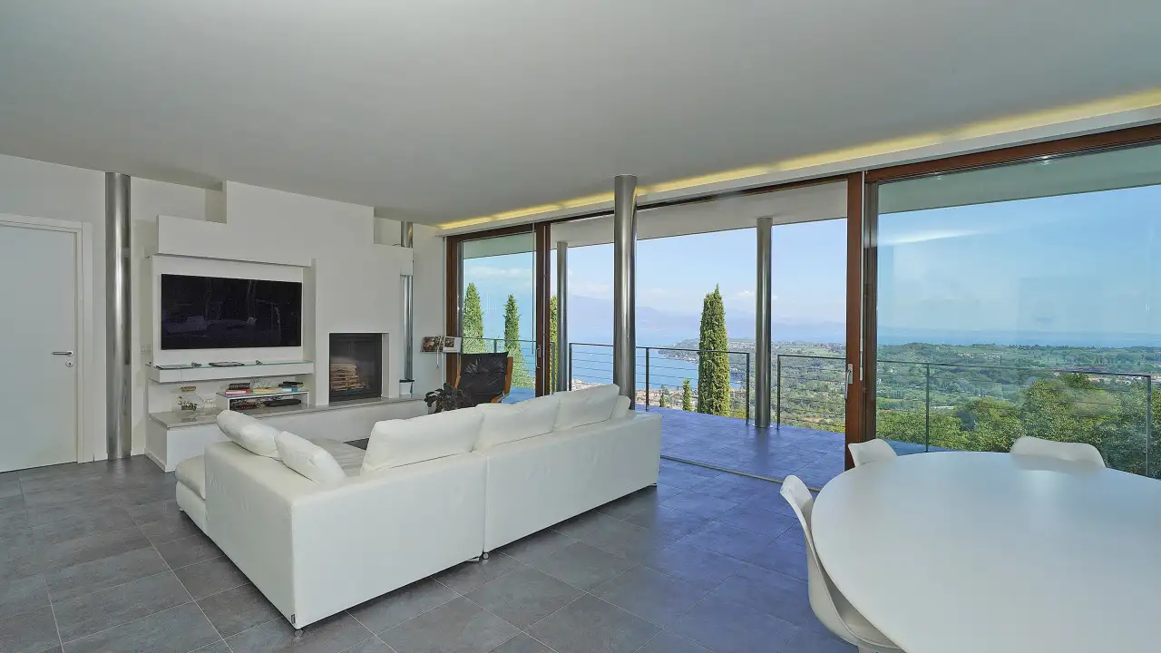 Wohnzimmer mit weißem Sofa, Kamin und Panoramafenstern