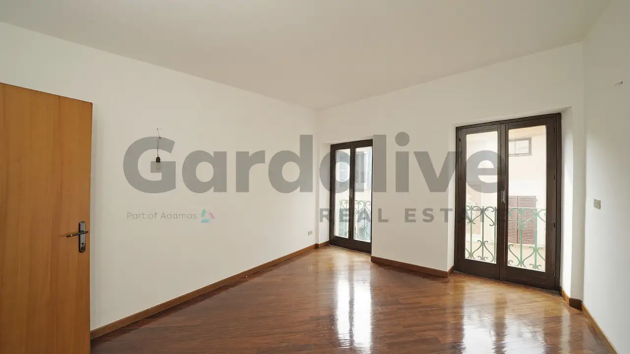 Soggiorno con pavimento in legno e due porte finestre con ringhiera in ferro battuto